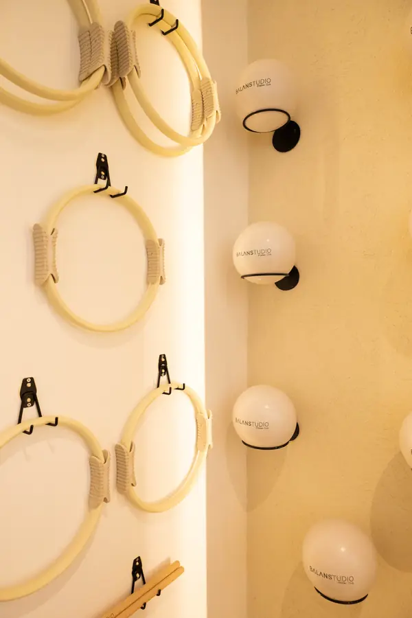 Anillos de Pilates y pelotas pequeñas organizados en la pared del estudio