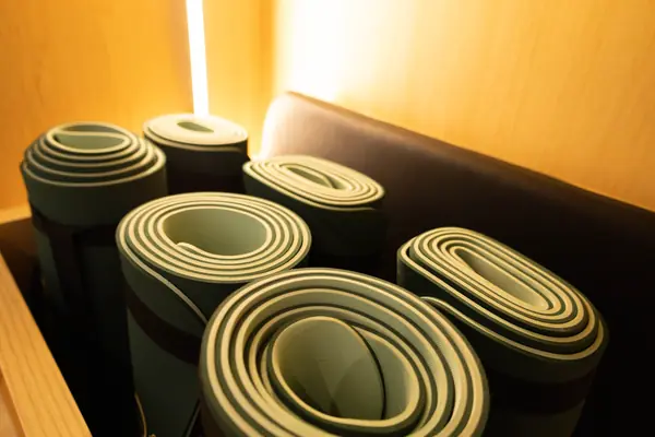 Mats enrollados en tonos verdes listos para clase de stretching o yoga